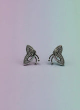 Pair of silver earrings with intricate designs on a gradient background