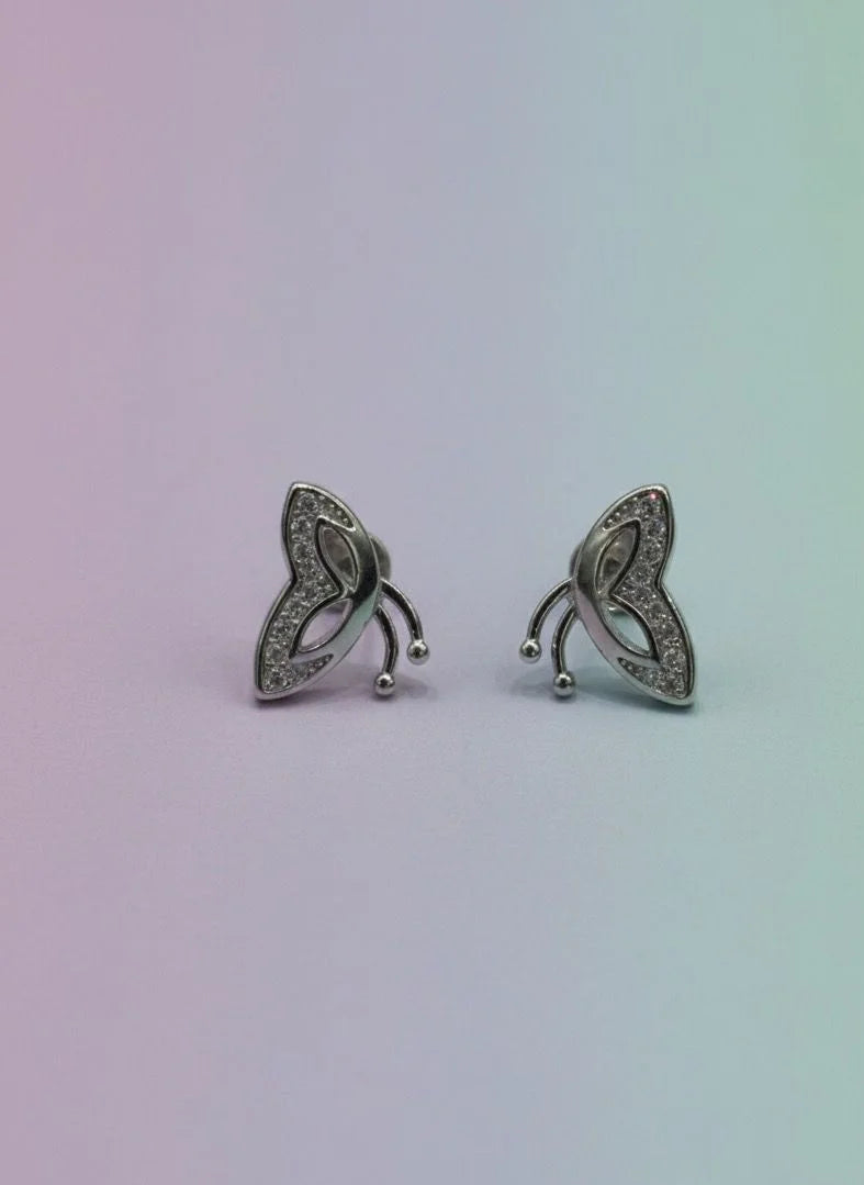 Pair of silver earrings with intricate designs on a gradient background