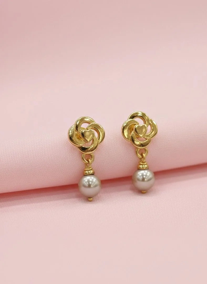 Gold earrings with pearl drops on a pink background