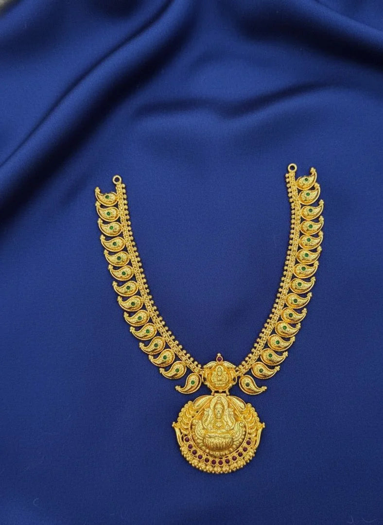 Gold necklace with a large pendant on a blue fabric background
