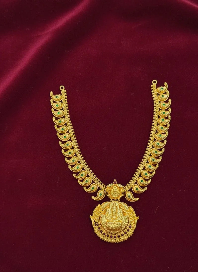 Gold necklace with green gemstones on a red fabric background