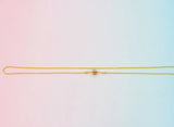 Gold mugappu chain on a gradient pink to blue background