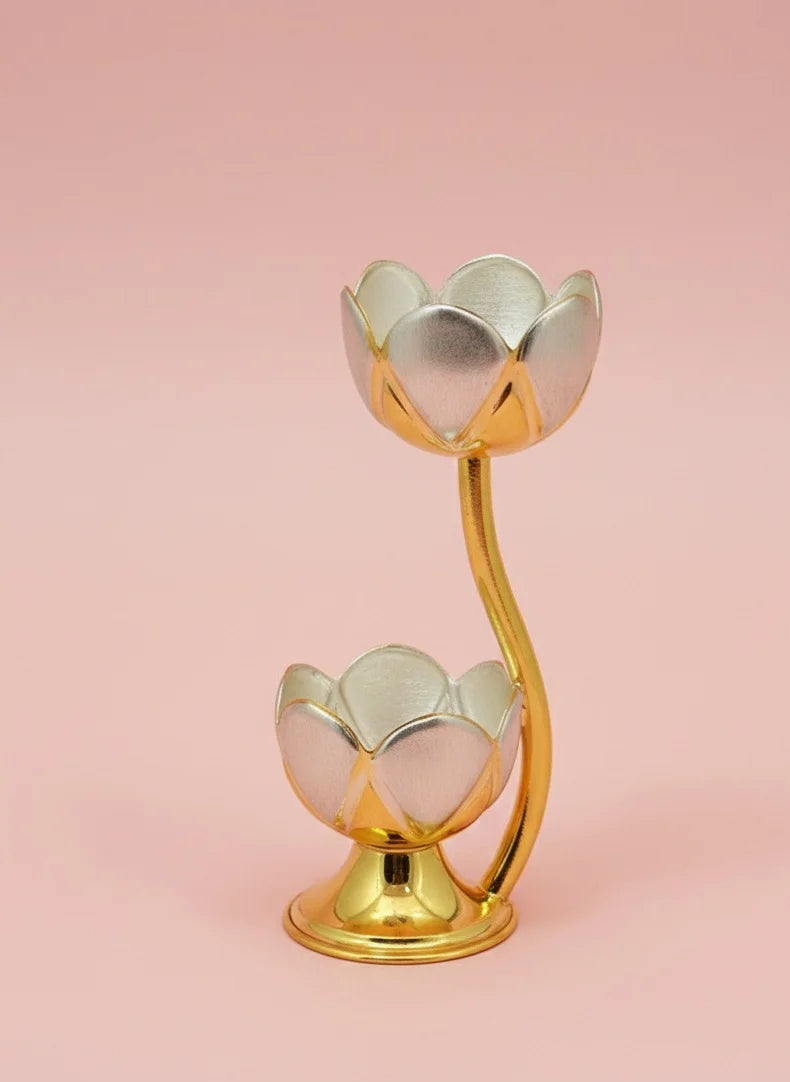 Gold and silver lotus-shaped candle holder on a pink background