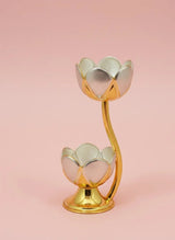 Gold and silver lotus-shaped candle holder on a pink background
