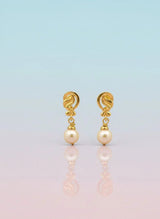 Gold earrings with pearl drops on a gradient background