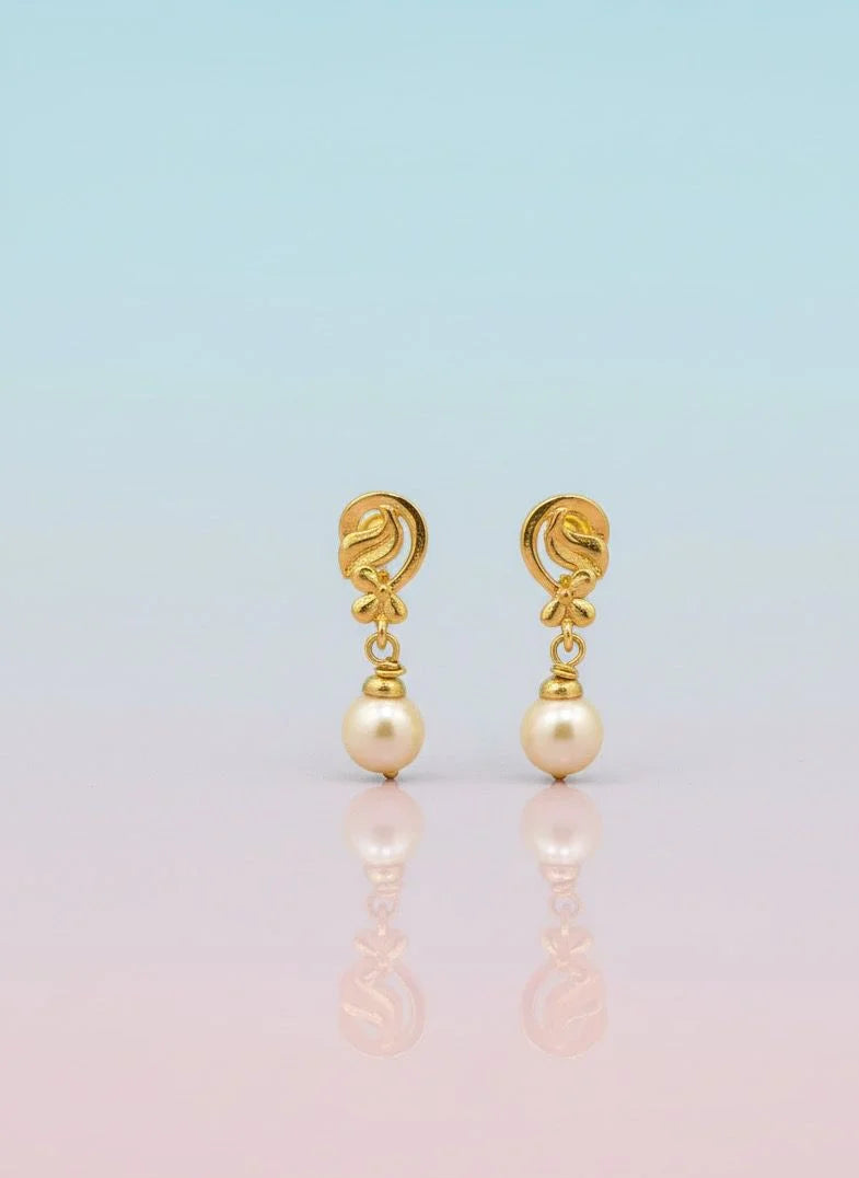 Gold earrings with pearl drops on a gradient background