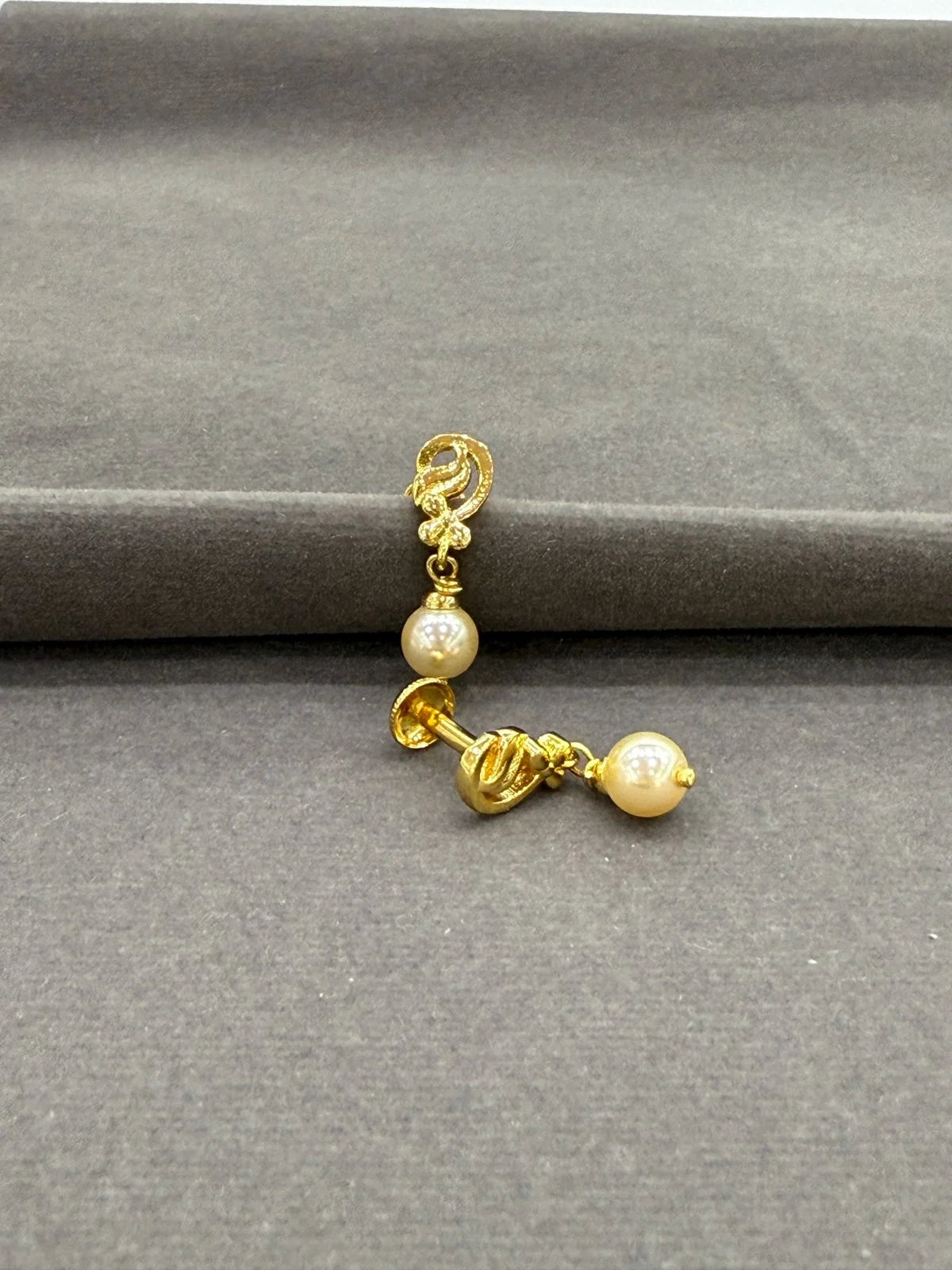 Gold earring with pearls on a gray background