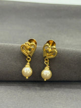Gold earrings with pearl drops on a gray surface