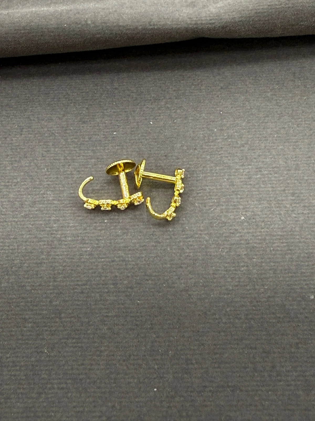 Gold earrings on a gray fabric background