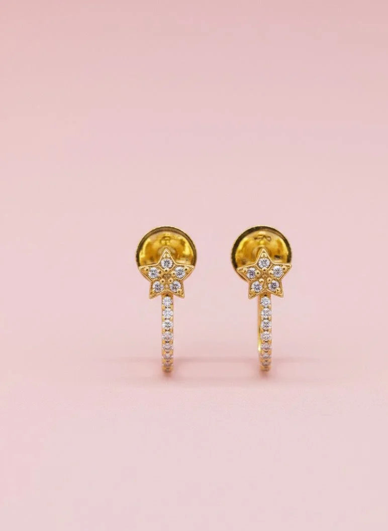 Gold earrings with gemstones on a pink background