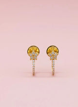 Gold earrings with gemstones on a pink background