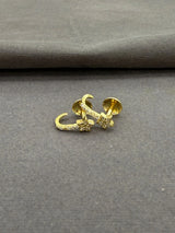 Gold earring on a gray fabric background