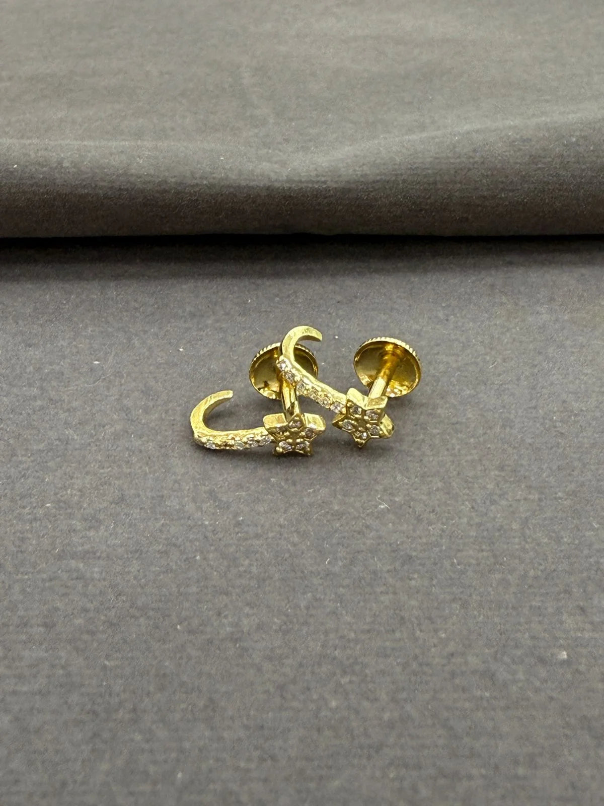 Gold earring on a gray fabric background