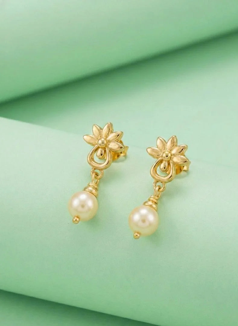 Gold earrings with pearl drops on a green fabric background