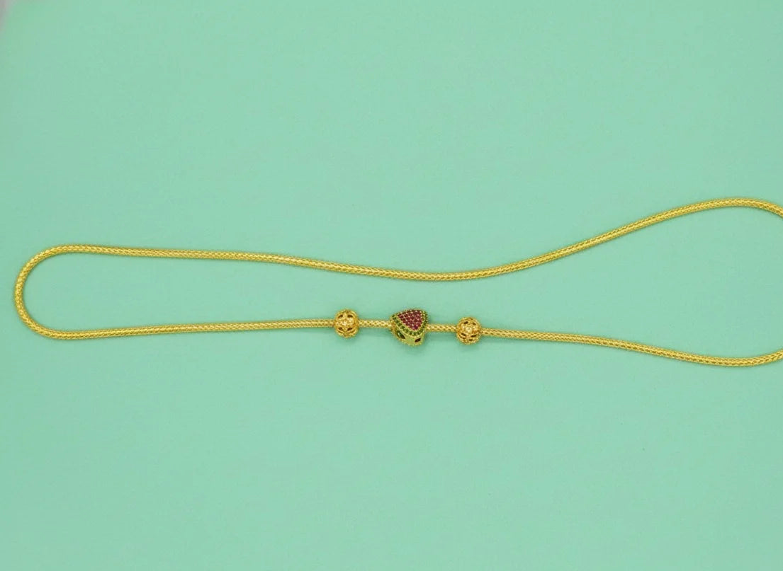 Gold necklace with a heart-shaped pendant on a light green background