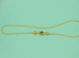 Gold necklace with a heart-shaped pendant on a light green background