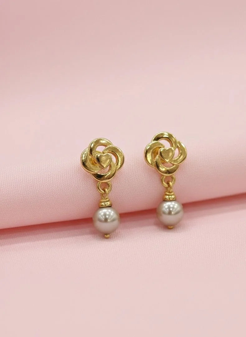 Gold earrings with pearl drops on a pink background
