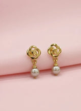 Gold earrings with pearl drops on a pink background