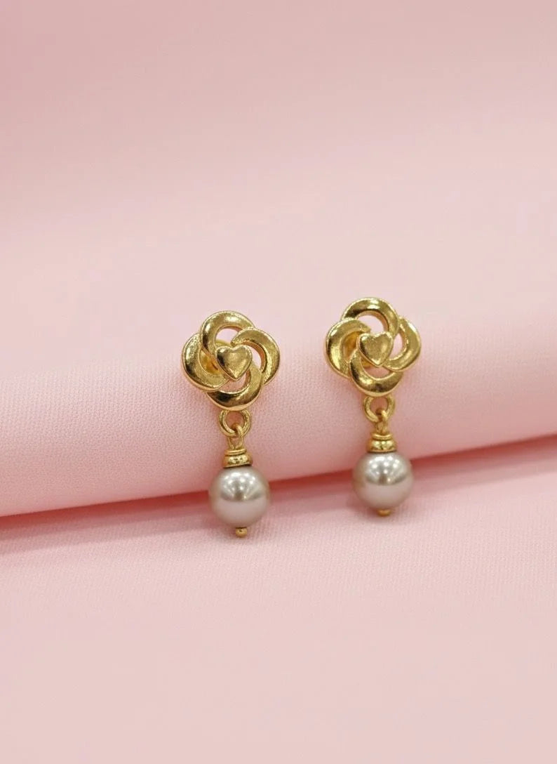 Gold earrings with pearl drops on a pink background