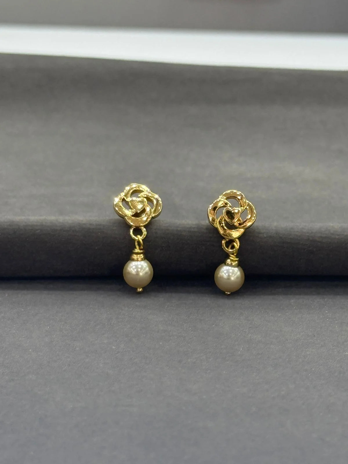 Gold earrings with pearl drops on a gray background