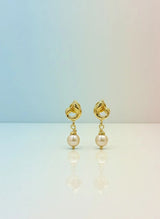 Gold earrings with pearl drops on a gradient background