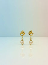 Gold earrings with pearl drops on a gradient background