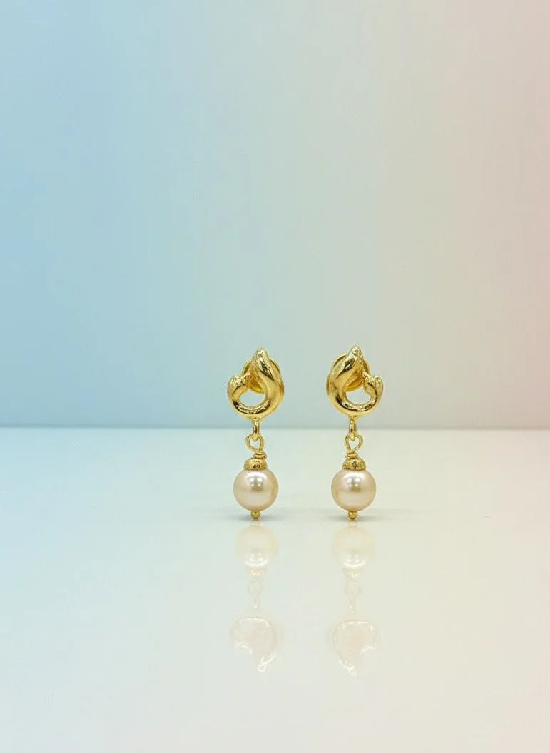 Gold earrings with pearl drops on a gradient background