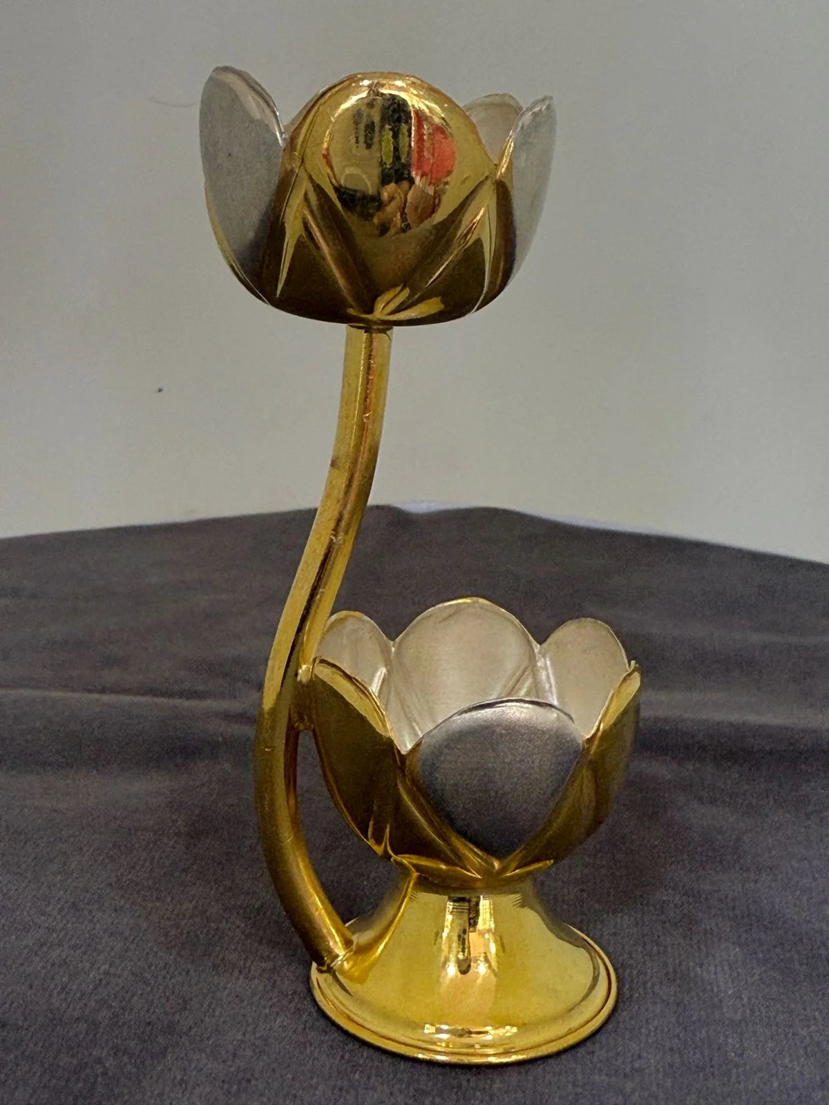 Gold flower-shaped candle holder on a gray surface