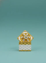 Decorative object with gold and white design on a teal background