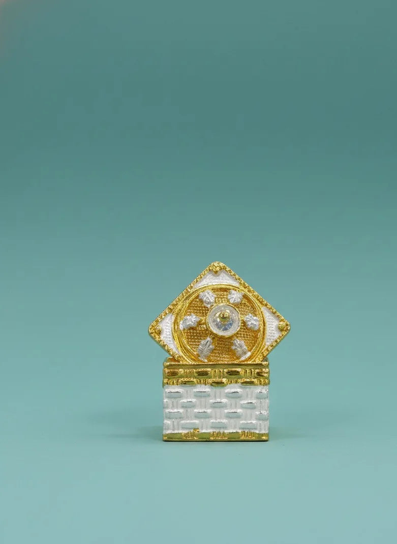 Decorative object with gold and white design on a teal background