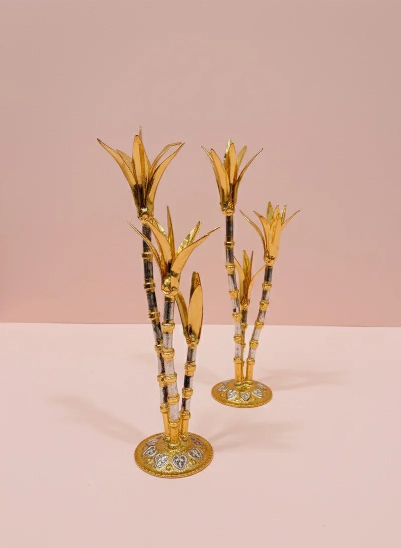 Decorative gold and black bamboo-like candle holders on a pink background