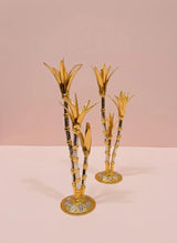 Decorative gold and black bamboo-like candle holders on a pink background