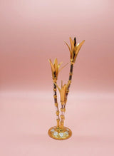Decorative gold and black bamboo-like object on a pink background