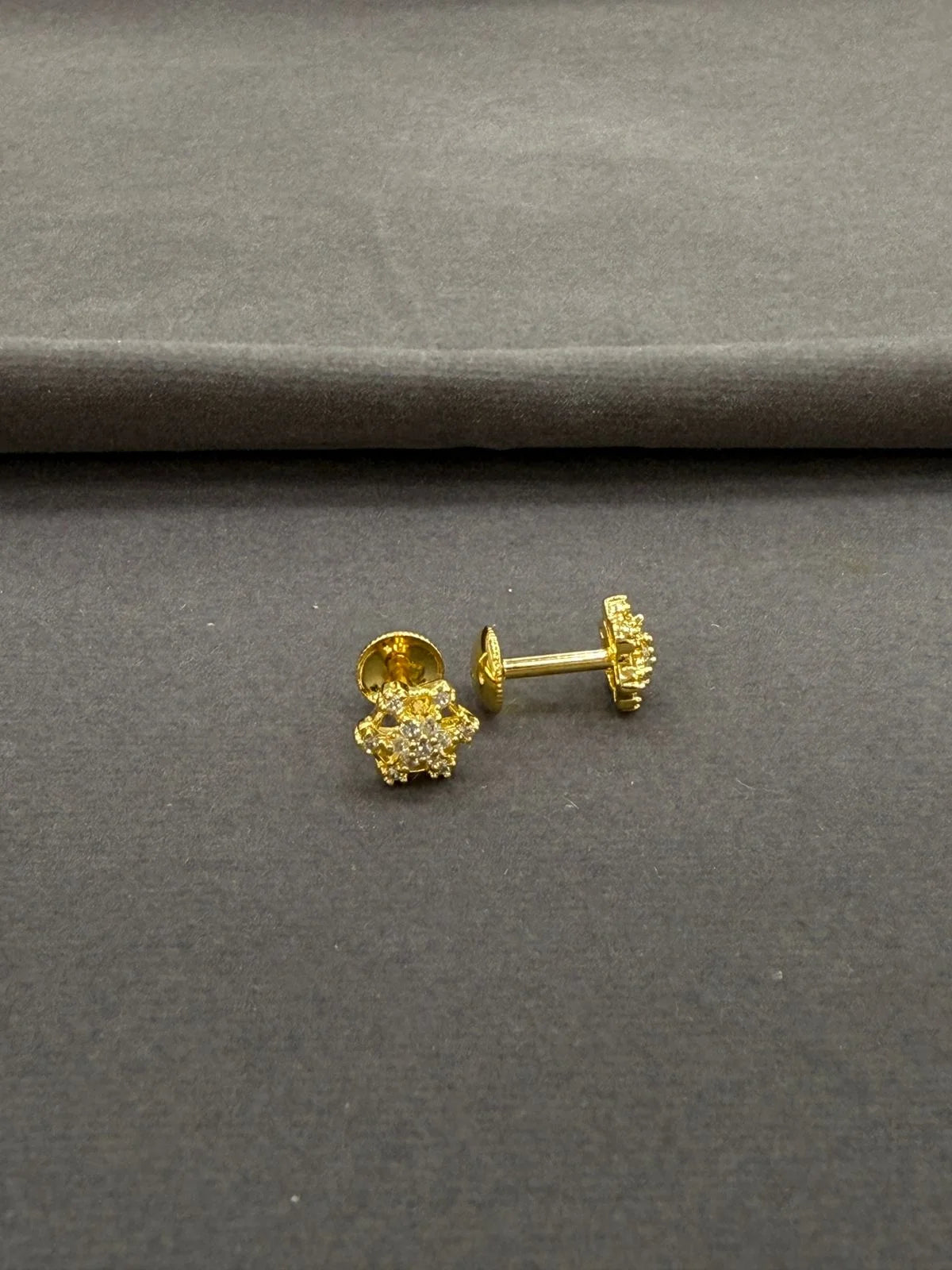Gold earrings on a gray surface