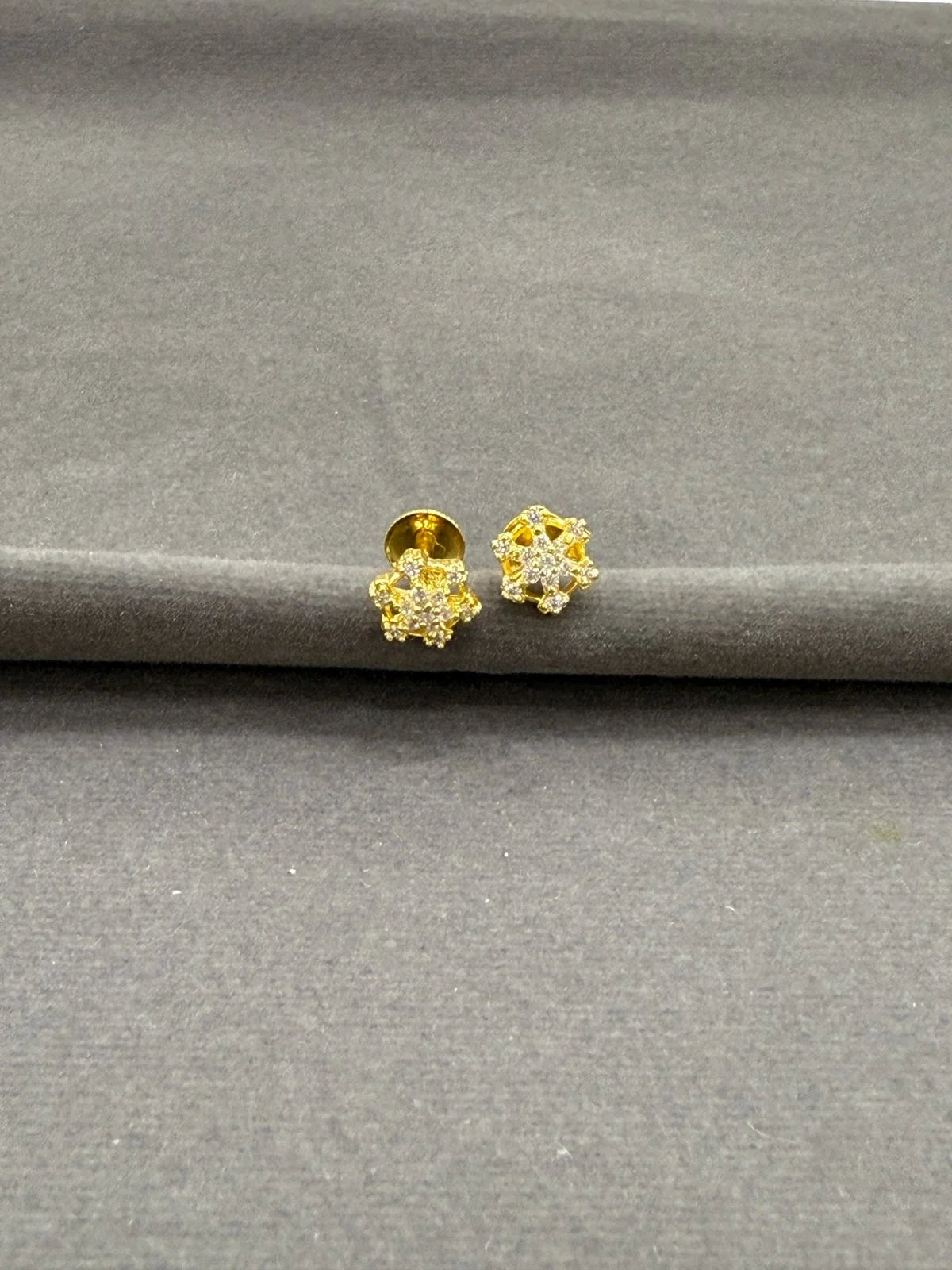 Gold earrings on a gray surface