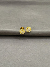 Gold earrings on a gray surface