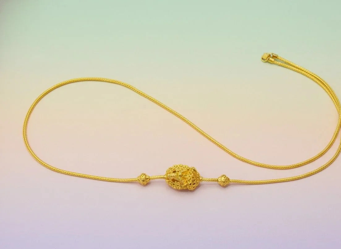 Gold necklace with intricate design on a gradient background