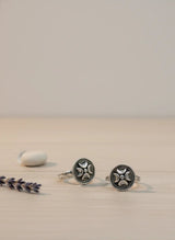 Silver toe rings with intricate designs on a beige surface with lavender.