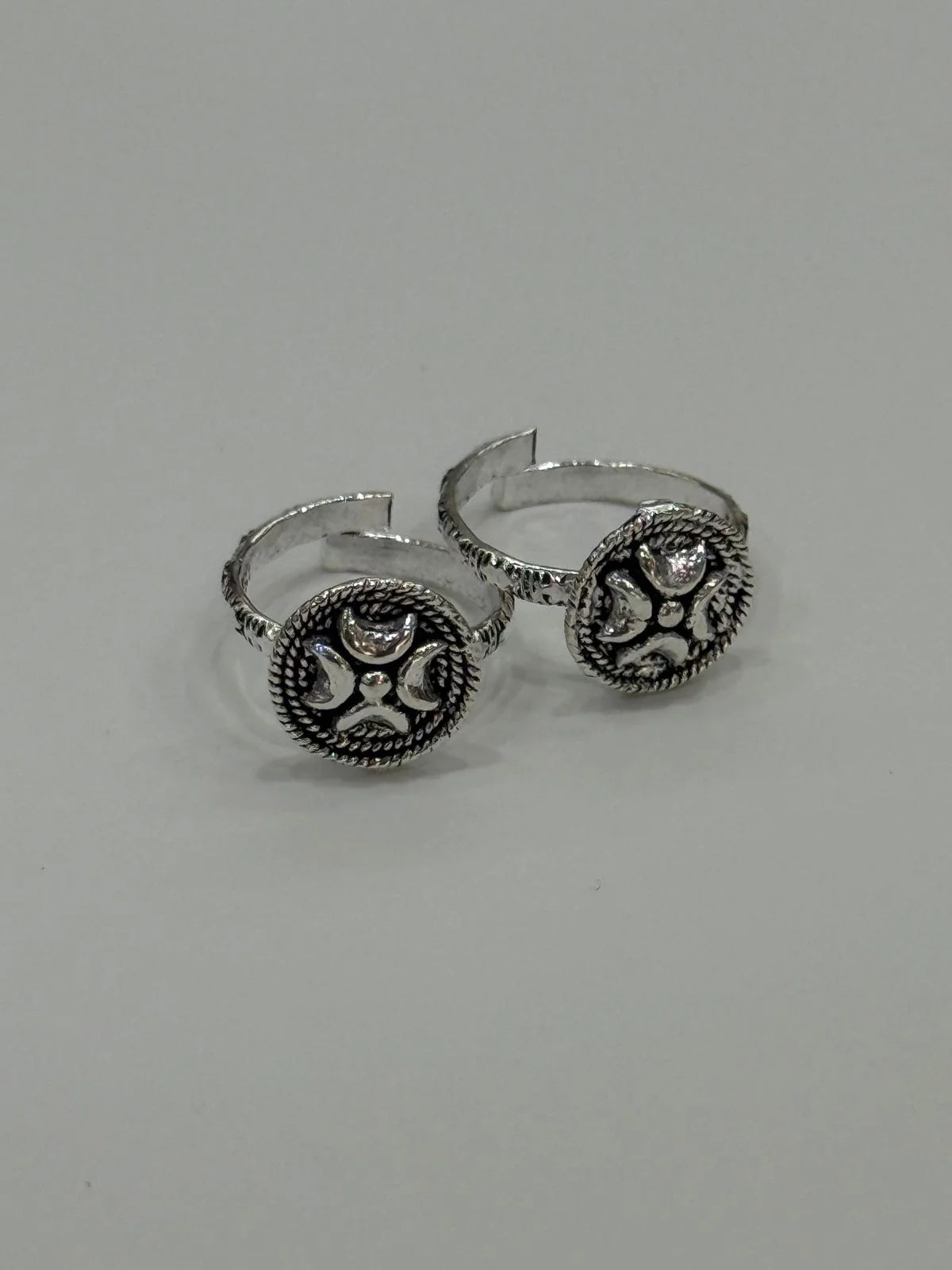 Pair of silver open-toe rings with decorative elements on a gray background