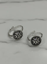 Pair of silver toe rings with intricate designs on a marble surface