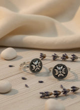 Two silver toe rings with intricate designs on a wooden surface with lavender and stones.