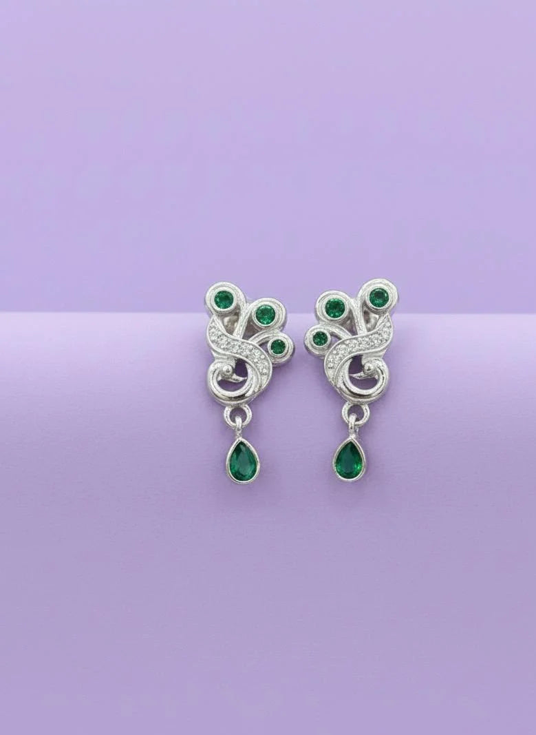 Pair of silver earrings with green gemstones on a purple background