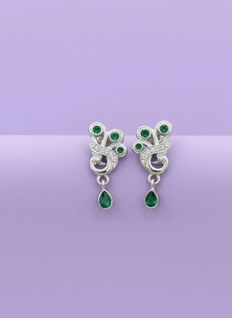 Pair of silver earrings with green gemstones on a purple background