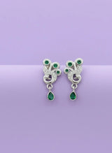 Pair of silver earrings with green gemstones on a purple background