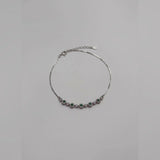 Silver bracelet with green and purple stones on a light gray background