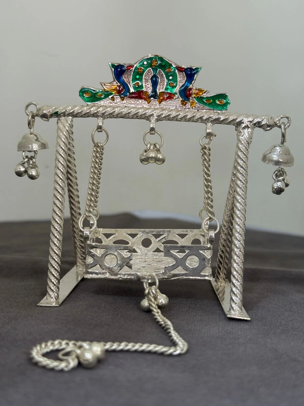 Decorative silver swing with colorful top on a gray background