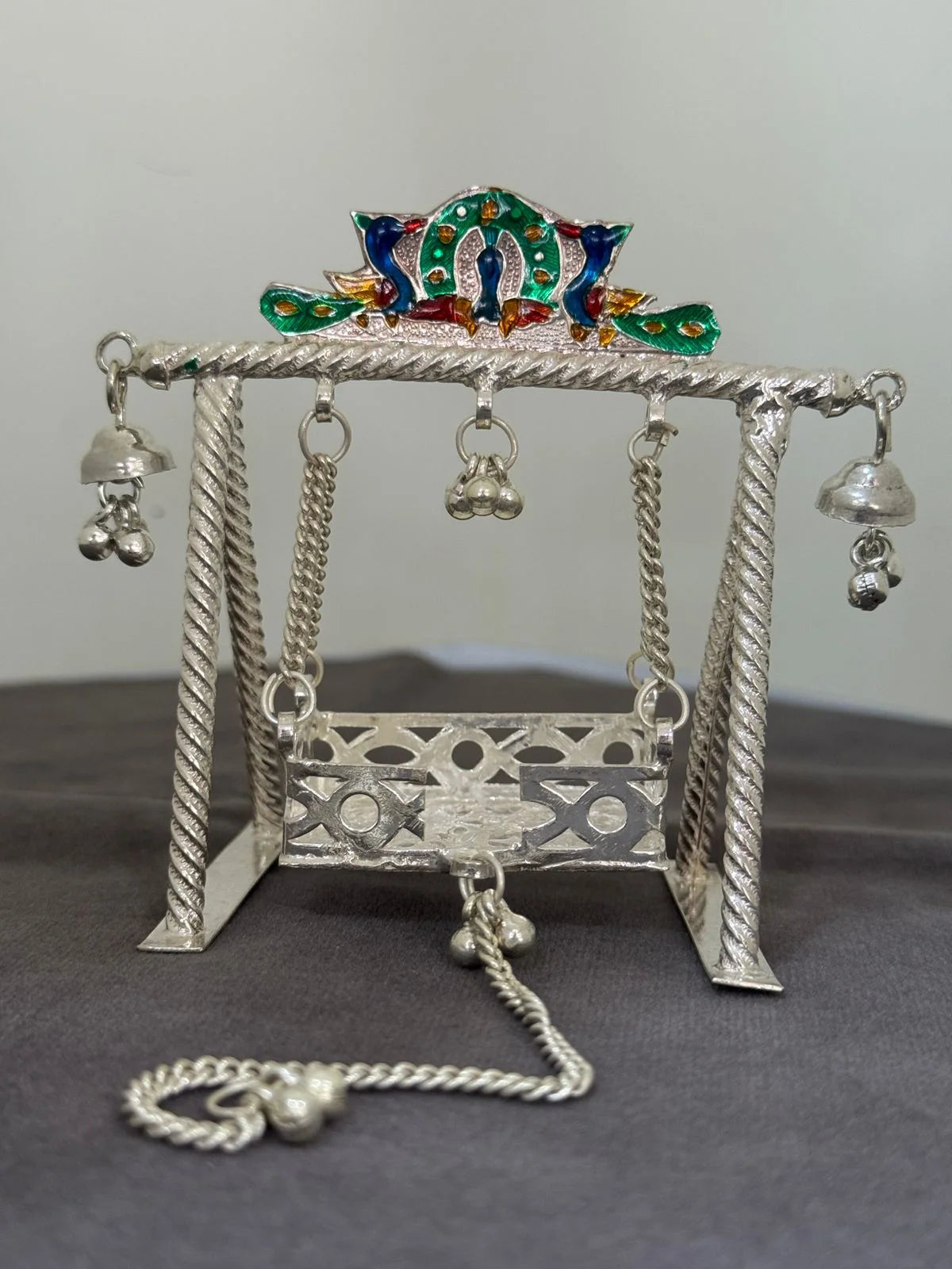 Decorative silver swing with colorful top on a gray background
