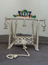 Decorative silver swing with colorful top on a gray background