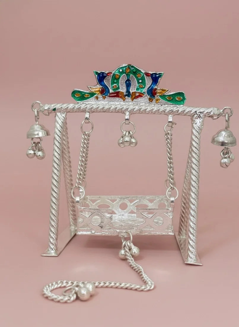Decorative silver swing with peacock top on a pink background