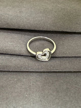Silver ring with a heart-shaped design on a gray surface